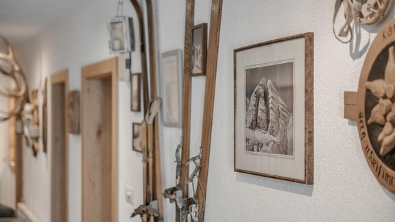 A stylish hallway with wooden skis and decorative wall pictures. The walls are adorned with traditional elements and memorabilia. - Pension Charly - Sölden