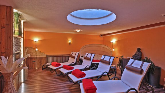 A relaxing wellness area with loungers and red towels. A skylight provides pleasant light in the room. - Pension "Zur alten Mühle" - Sölden