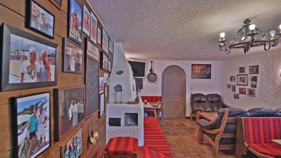 A cozy room with wooden paneling and many pictures on the wall. There are comfortable seats and a warm, inviting atmosphere. - Pension "Zur alten Mühle" - Sölden