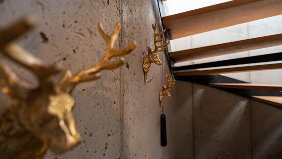 Eine elegante Treppe mit modernen, goldenen Wanddekorationen. Der Hintergrund ist aus Beton und schafft einen stilvollen Kontrast. - Selda Chalet - Sölden