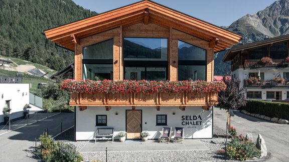 Ein modernes Chalet mit Holzverkleidung und großen Fenstern. Es ist von schönen Bergen und Blumen umgeben. - Selda Chalet - Sölden