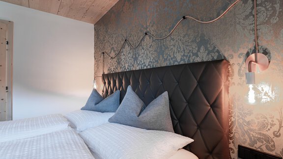 Ein modernes Schlafzimmer mit einem stilvollen, gepolsterten Kopfteil und geschmackvoller Wanddekoration. Sanfte Beleuchtung schafft eine gemütliche Atmosphäre. - Selda Chalet - Sölden