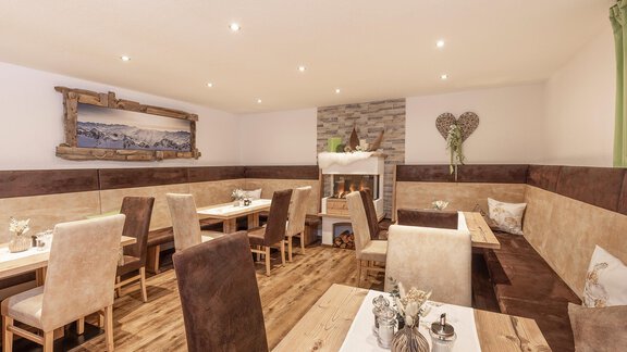 A cozy breakfast room with bright wooden tables and comfortable chairs. - Trofana Appartements - Sölden