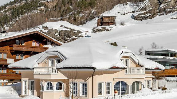 Ein schönes Haus im Schnee, umgeben von Bergen und Bäumen. Der Himmel ist klar mit einigen Wolken. - Villa Castelbell - Sölden