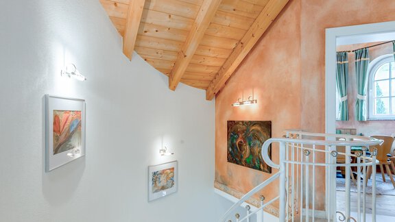 Eine elegante Treppe mit Holzdecke und Kunstwerken an den Wänden. Der Raum ist hell und einladend. - Villa Castelbell - Sölden