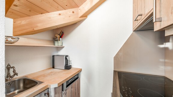 Eine kleine, moderne Küche mit einem Holzdecke und hellen Möbeln. Sie enthält eine Spülbecken, ein Kochfeld und einen Geschirrspüler. - Villa Castelbell - Sölden