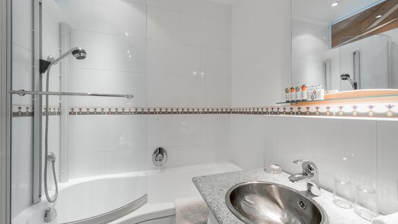 Ein modernes Badezimmer mit einer Dusche und einer Badewanne. Der Waschbeckenbereich ist mit einer eleganten Steinoberfläche ausgestattet. - Villa Castelbell - Sölden
