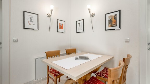 Ein heller Essbereich mit einem Holztisch und vier Stühlen. An der Wand hängen mehrere Bilder, und die Beleuchtung sorgt für eine gemütliche Atmosphäre. - Villa Castelbell - Sölden