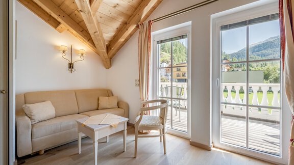 Ein gemütlicher Wohnraum mit einem hellen Sofa und einem kleinen Tisch. Große Fenster bieten einen Blick auf die umliegenden Berge. - Villa Castelbell - Sölden