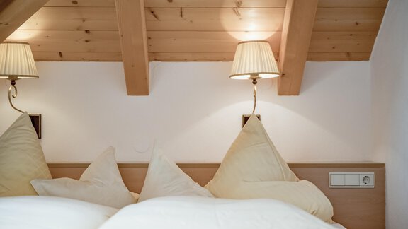 Ein gemütliches Schlafzimmer mit weichen Kissen und warmem Licht. Die Holzdecke schafft eine einladende Atmosphäre. - Villa Castelbell - Sölden