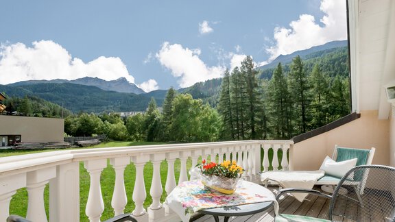 Ein Balkon mit schöner Aussicht auf Berge und Bäume. Ein Tisch mit Blumen und Stühlen lädt zum Entspannen ein. - Villa Castelbell - Sölden