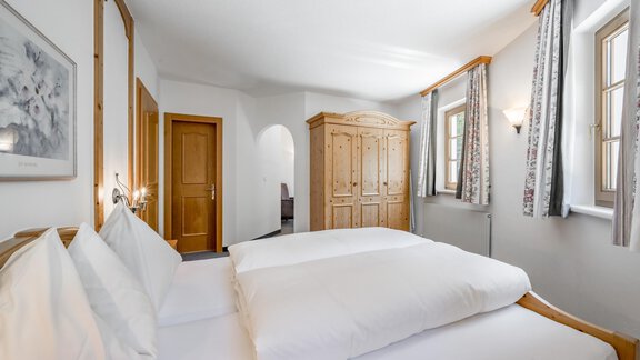 A cozy bedroom with a double bed and white bedding. The room is bright and friendly, with wood-accented furniture and windows that let in daylight. - Waldhäusl - Sölden