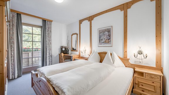 A cozy bedroom with a double bed and wood paneling. Large windows provide plenty of daylight and a pleasant atmosphere. - Waldhäusl - Sölden