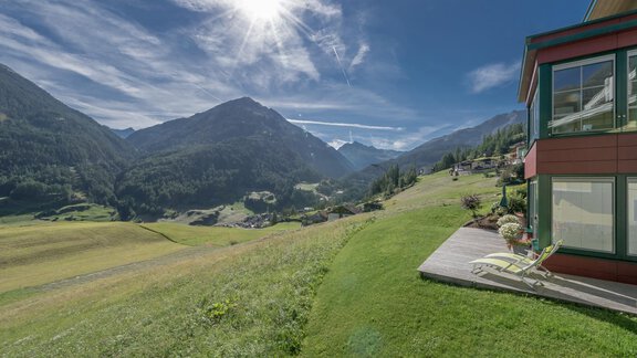 Eine idyllische Landschaft mit grünen Wiesen und Bergen im Hintergrund. Der Himmel ist klar und sonnig, und ein Gebäude steht im Vordergrund. - zuckerhütl NATURAPPART - Sölden