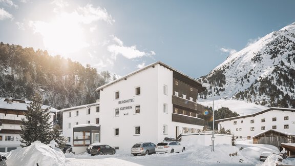 A modern building in the snow with mountains in the background. The sun is shining on the snowy landscape. - Berghotel Gstrein - Vent