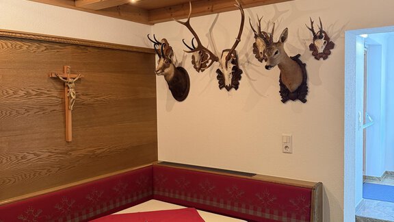 A typical room with wooden paneling and a cozy seating area. Antlers hang on the wall, creating an alpine atmosphere. - Mein Weisskugel - Vent