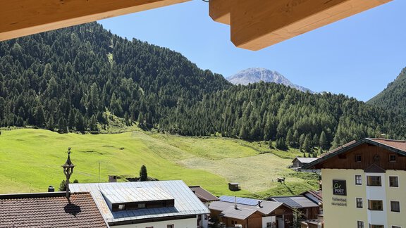 A beautiful view of green hills and mountains. In the foreground are traditional houses and a clear blue sky. - Mein Weisskugel - Vent