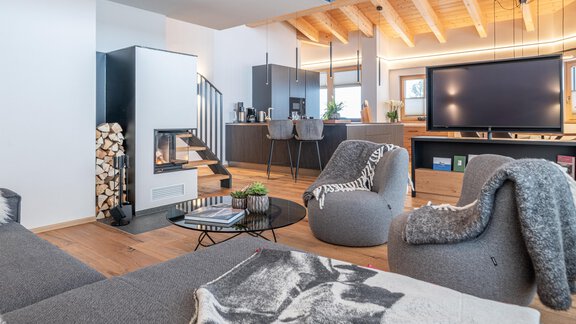 Ein modernes Wohnzimmer mit gemütlichen Sitzmöbeln und einem Kamin. Die offene Küche und große Fenster sorgen für eine helle, einladende Atmosphäre. - Weinleins Hof - Vent