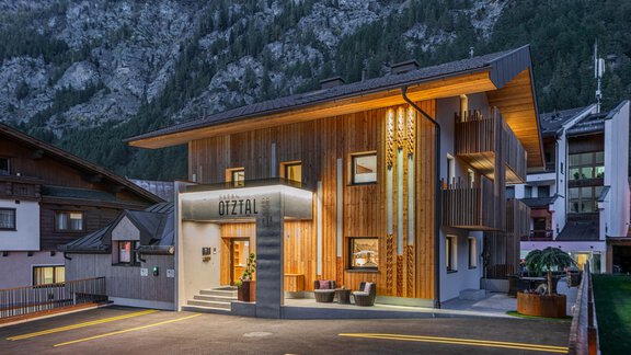 Ein modernes Holzgebäude in den Bergen, das als Unterkunft dient. Die Fassade ist gut beleuchtet und zeigt einen einladenden Eingang. - Garni Ötztal ROOMS & APARTS - Zwieselstein