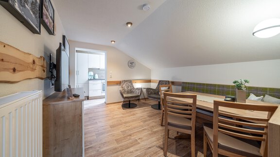 A cozy living space with a dining table and chairs. The walls are light and there are large windows that flood in a lot of light. - Garni Ötztal ROOMS & APARTS - Zwieselstein