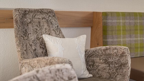 A cozy armchair with a decorative cushion. The environment is bright and friendly designed. - Garni Ötztal ROOMS & APARTS - Zwieselstein