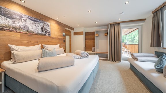 A modern bedroom with two beds and large windows. The room features bright wood decor and a cozy atmosphere. - Garni Ötztal ROOMS & APARTS - Zwieselstein