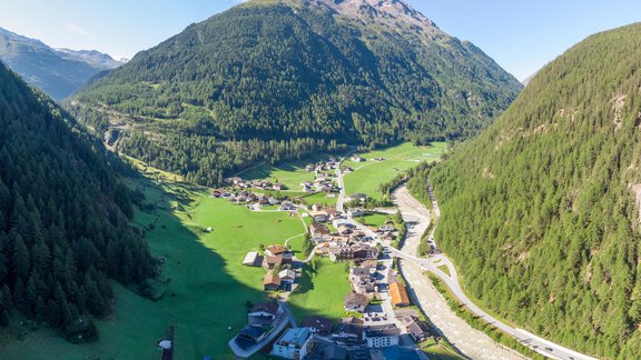 Eine malerische Berglandschaft mit einem kleinen Dorf im Tal. Die Umgebung ist grün und von hohen Bergen umgeben. - Garni Ötztal ROOMS & APARTS - Zwieselstein