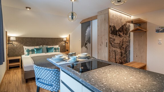 A modern room with a comfortable bed and an elegant kitchenette. The warm colors and stylish decor create an inviting atmosphere. - Garni Ötztal ROOMS & APARTS - Zwieselstein