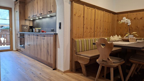 Eine gemütliche Küche mit Holzmöbel und einer Sitzgruppe. Sie ist hell und einladend, perfekt für gemeinsame Mahlzeiten. - Landhaus Alpenjäger - Zwieselstein