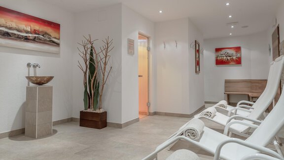 Ein moderner, entspannender Raum mit Liegen und sanfter Beleuchtung. An den Wänden hängen dekorative Bilder, und Pflanzen schaffen eine ruhige Atmosphäre. - Pension Michael - Obergurgl 