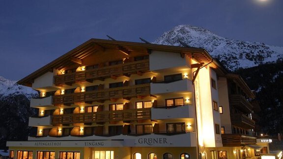 Ein gemütliches Hotel mit beleuchteten Balkonen inmitten einer bergigen Landschaft. Der Himmel ist klar und der Mond leuchtet in der Nacht. - Alpengasthof Grüner - Sölden