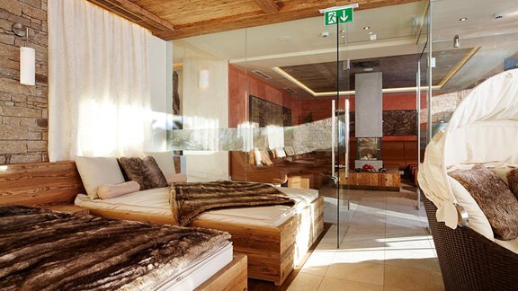 A modern wellness area with wooden loungers and calming colors. Large windows let in plenty of daylight and create a relaxed atmosphere. - Alpengasthof Grüner - Sölden