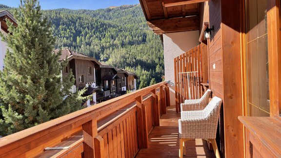 A beautiful balcony with two chairs and a view of a forested mountain landscape. The sun is shining and the sky is clear. - HAUS ERIKA apartments - Sölden