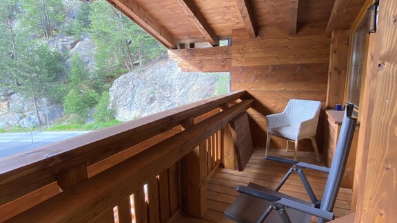 A wooden balcony with a chair and a lounger. The surroundings are surrounded by nature and convey a peaceful atmosphere. - HAUS ERIKA apartments - Sölden