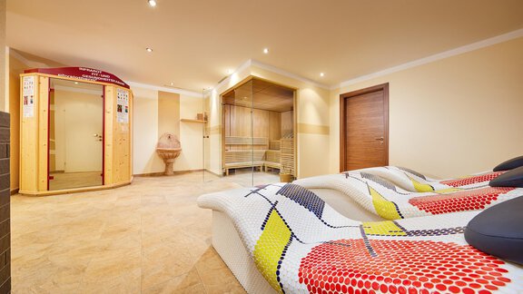 A bright wellness room with modern loungers. In the background, there is a sauna and a steam bath. - Hotel Sunny Sölden - Sölden