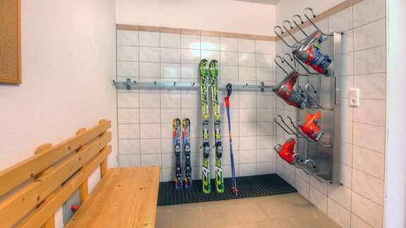 Ein Skiraum mit mehreren Skiern und Helmen an einer Wand. Es gibt eine Holzbank für das Sitzen und Anziehen der Ausrüstung. - Appt.  Ferienglück - Sölden