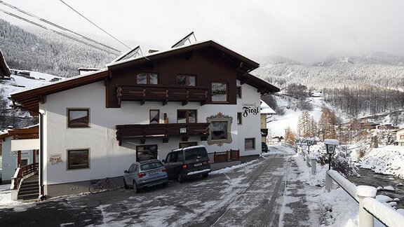Ein rustikales Gebäude im Schnee mit einem großen Balkon. Die Umgebung ist von schneebedeckten Bergen umgeben. - Landhaus Fiegl - Sölden
