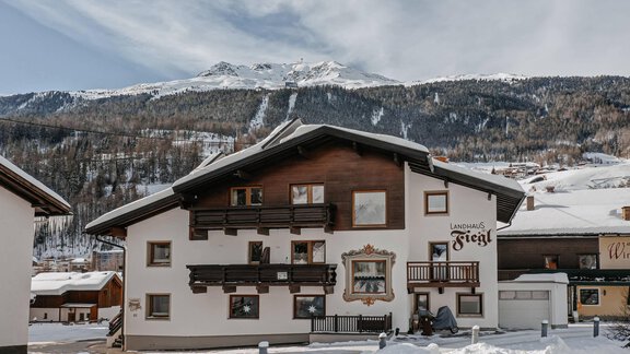 Ein charmantes Gebäude in den Bergen, umgeben von schneebedeckten Landschaften. Der klare Himmel und die beeindruckenden Berge im Hintergrund schaffen eine malerische Winteratmosphäre. - Landhaus Fiegl - Sölden