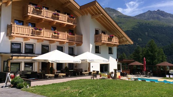 Ein gemütliches Hotel mit Holzverkleidung und Balkonen. Im Hintergrund sind malerische Berge und ein Außenpool zu sehen. - Pension Waldesruh - Sölden