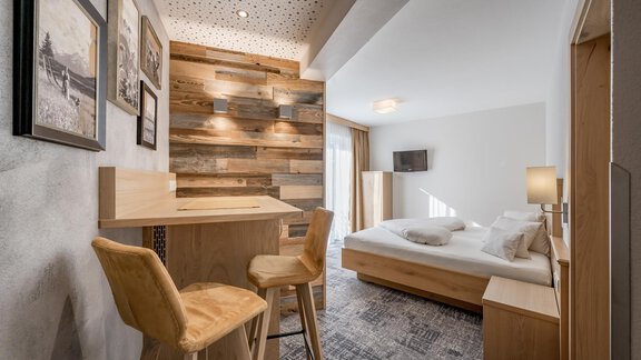 Ein modernes Zimmer mit einem großen Bett und einer gemütlichen Sitzecke. Holzwände und geschmackvolle Dekoration verleihen dem Raum eine einladende Atmosphäre. - Residenz Allegra - Sölden