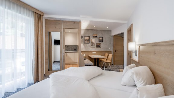 Ein modernes Hotelzimmer mit einem großen Bett und hellem Holzdesign. Es gibt einen Tisch und Stühle sowie einen großen Balkon mit viel Licht. - Residenz Allegra - Sölden