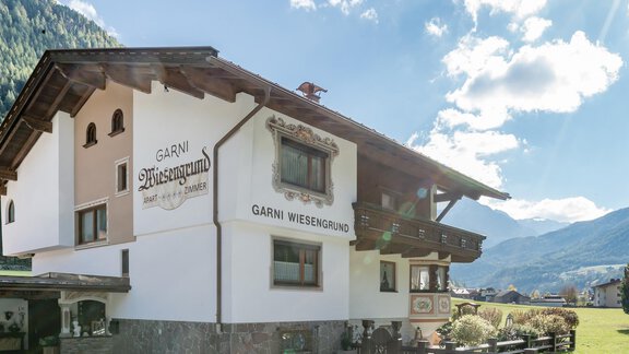 Ein traditionelles Gästehaus mit dem Namen "Garni Weisengrund" in malerischer Berglandschaft. Die Fassade zeigt einen charmanten alpenländischen Stil und die Umgebung ist grün und einladend. - Apart Wiesengrund - Sölden