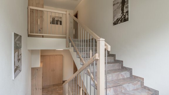 Ein heller Flur mit einer Treppe und Holzgeländer. An den Wänden hängen einige Bilder. - Residenz Allegra - Sölden | © Residenz Allegra Sölden