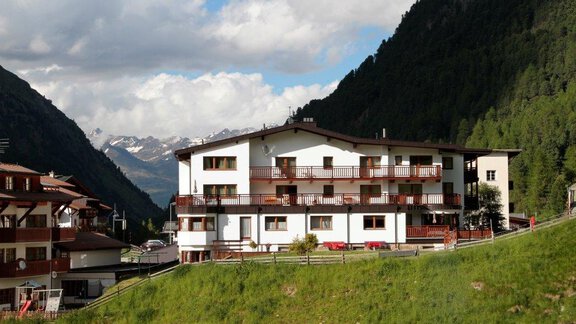 Ein schönes Gebäude in den Bergen mit Balkonen und umgeben von einer grünen Wiese. Im Hintergrund sind hohe Berge und ein bewölkter Himmel zu sehen. - Gästehaus Soldanella - Vent