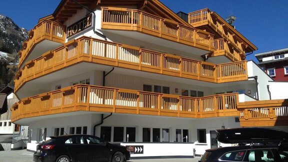 Ein modernes Hotel mit Holzverkleidung und mehreren Balkonen. Das Gebäude befindet sich in einer bergigen Umgebung mit einem klaren Himmel. - Hotel-Appartements A CASA "Saphir" - Sölden