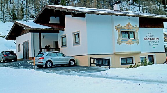 A cozy house in the mountains, surrounded by snow. Two cars are parked in the driveway. - Haus Benjamin - Zwieselstein