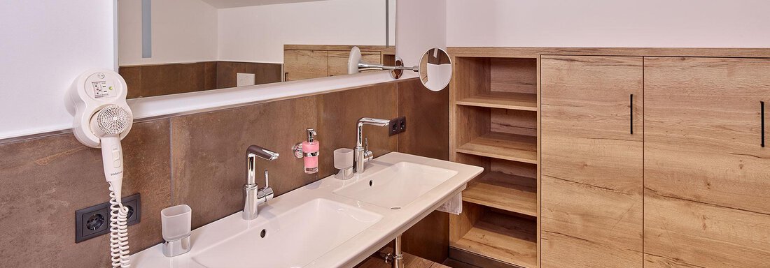 Ein modernes Badezimmer mit Doppelwaschbecken und Holzregalen. Die Wände sind in neutralen Farben gehalten, und die Einrichtung wirkt stilvoll und geräumig. - Alpenappartement Central Valley Penthouse - Längenfeld