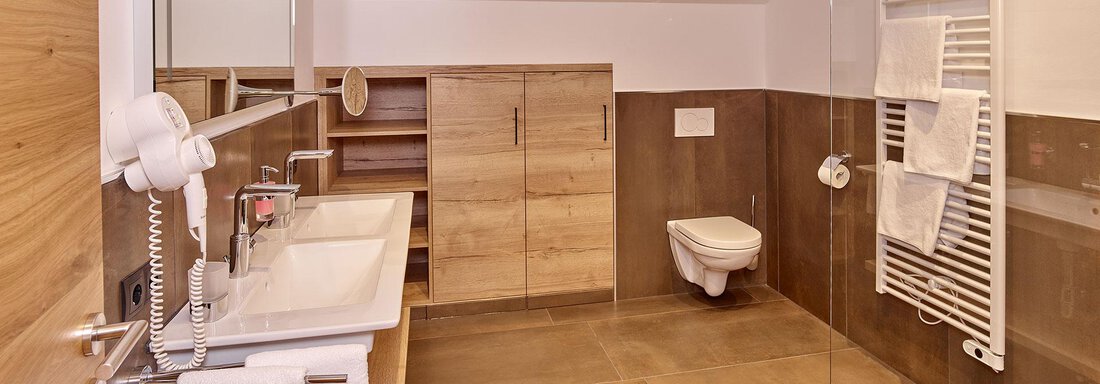 Ein modernes Badezimmer mit Holz- und Steinakzenten. Es verfügt über ein Waschbecken, eine Dusche und eine Toilette in einer hellen, offenen Gestaltung. - Alpenappartement Central Valley Penthouse - Längenfeld