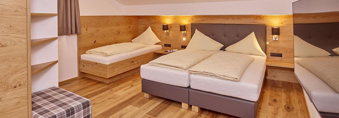 Ein gemütliches Schlafzimmer mit zwei Betten und Holzfußboden. Die Wände sind in warmen Tönen gehalten und es gibt genügend Stauraum. - Alpenappartement Central Valley Penthouse - Längenfeld