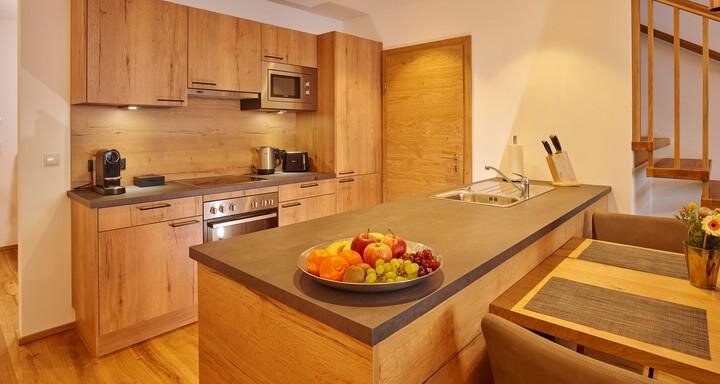 Eine moderne Küche mit Holzmöbeln und einem großen Kücheninseln. Auf dem Tisch steht eine Schüssel mit frischem Obst. - Alpenappartement Central Valley Penthouse - Längenfeld